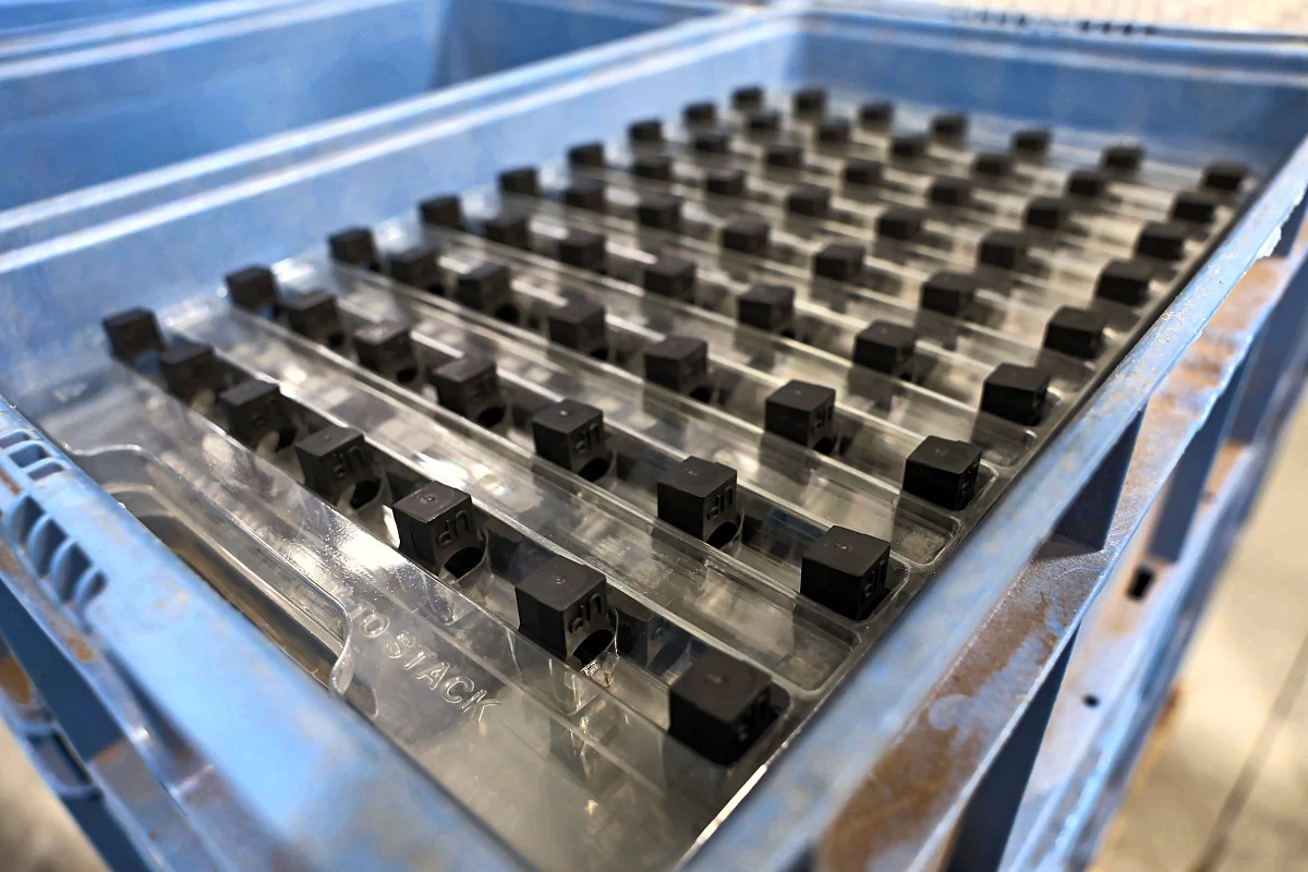 Close view of small black parts laid out in rows in a blue tray